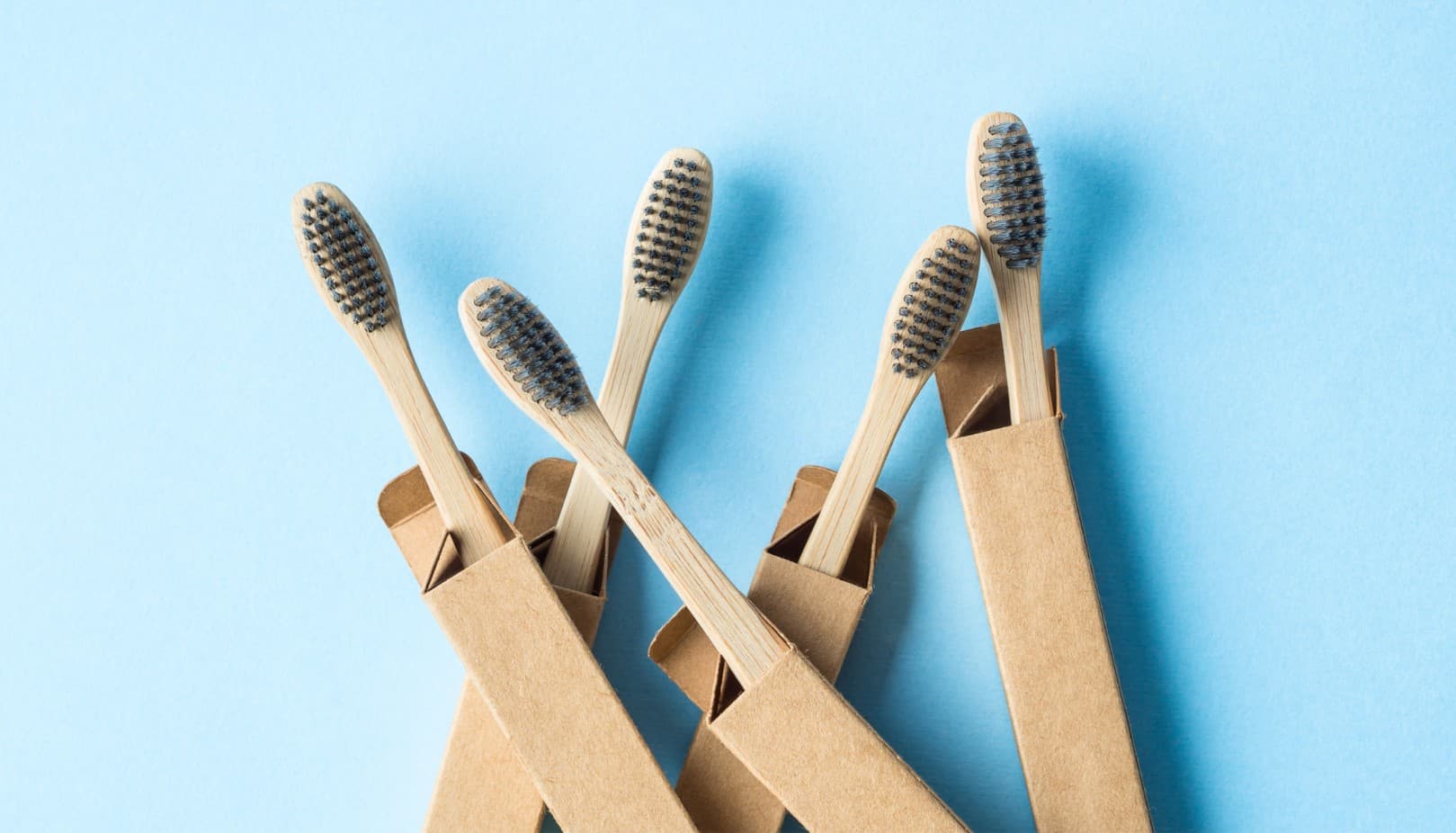 Bamboo toothbrush, comb and bowl with bamboo leaf on beige surface