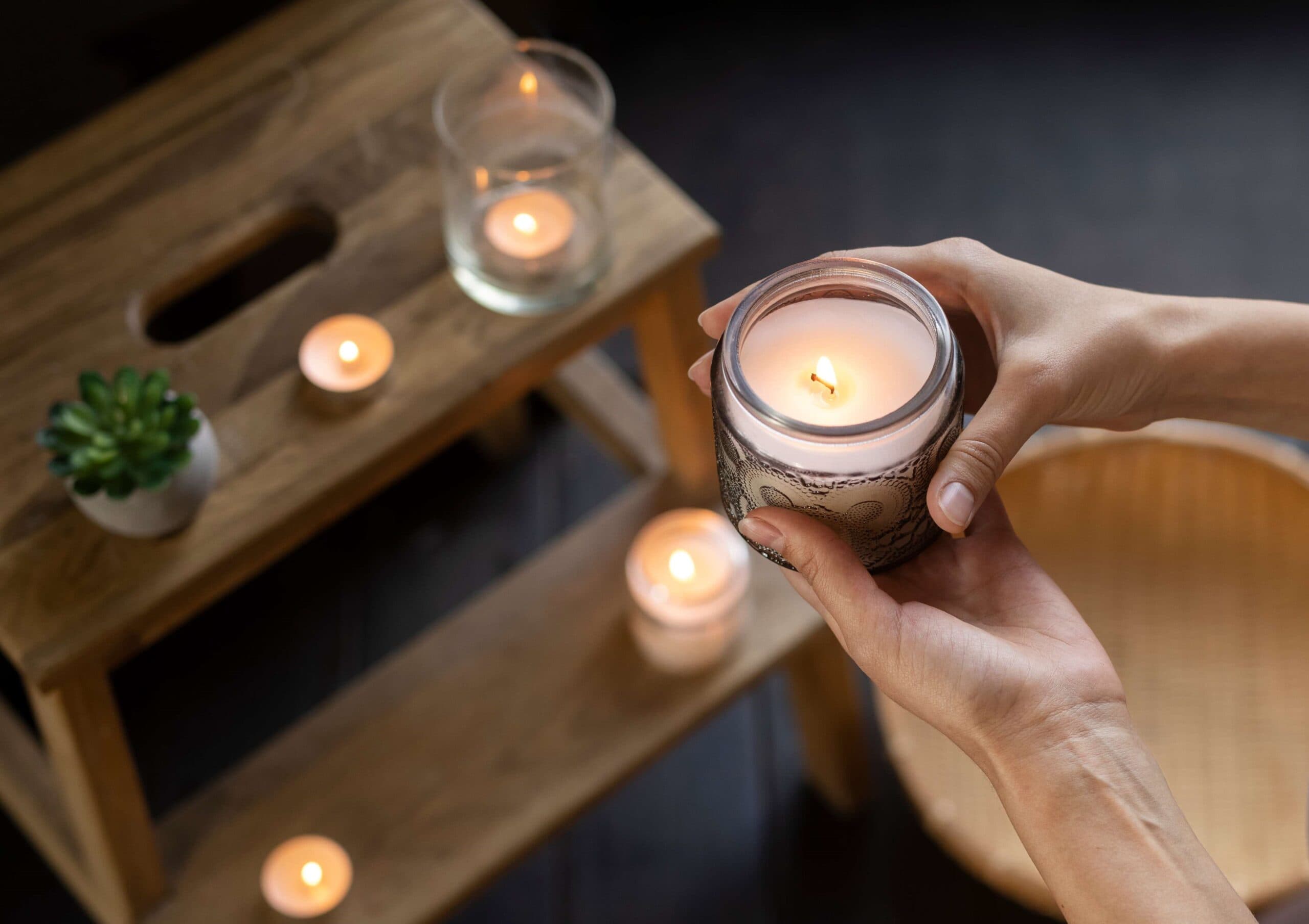 Person holding a lit soy jar candle on wooden steps
