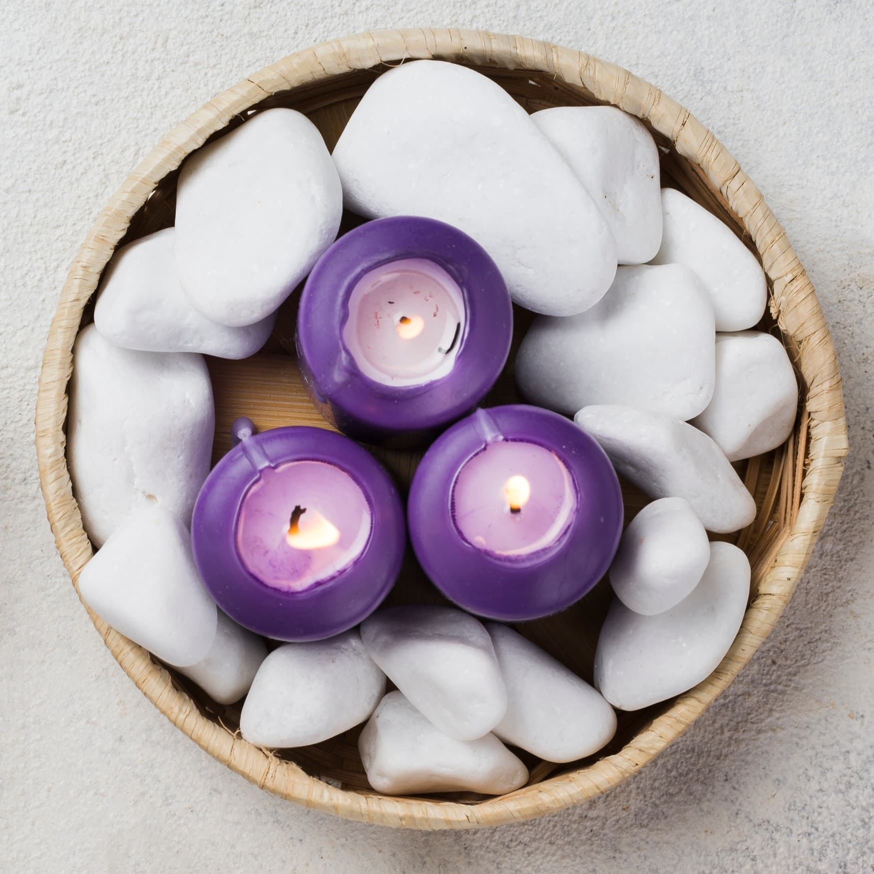 Person holding a lit soy candle in a glass jar on a wooden table